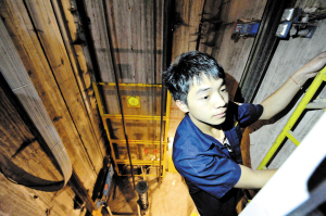 电梯维保员在黑漆漆的地坑里检修电梯。